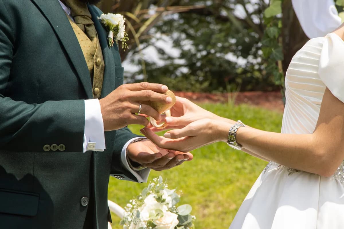 Bride and groom exchanging wedding rings outdoors