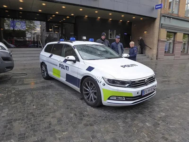 White police car parked with people beside it