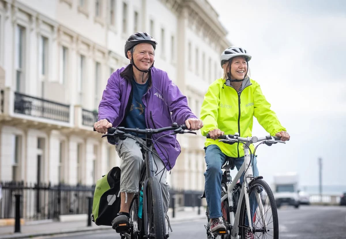 Senior adults wearing helmets cycling on a city street