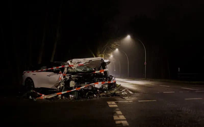 Damaged white car wrapped in caution tape on dark street at night