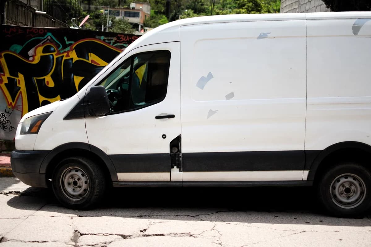 A white delivery van parked beside a colorful graffiti wall in an urban area.