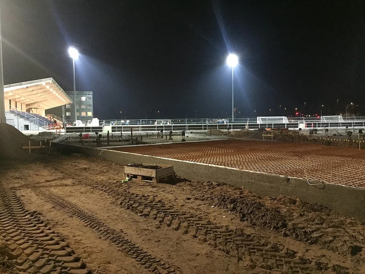 Køge Stadium under renovation at night with construction materials and lighting