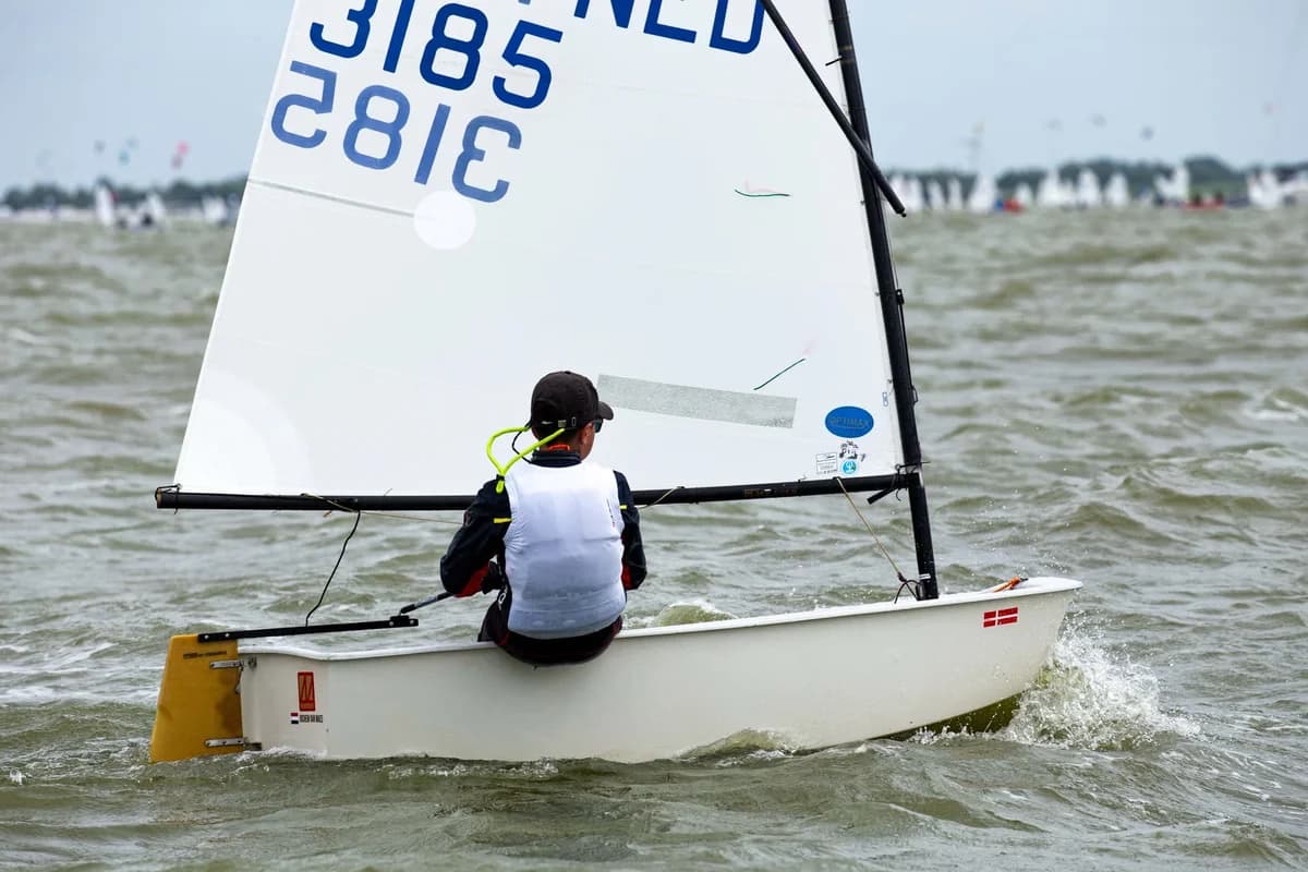 Young sailor sailing a dinghy through choppy water.